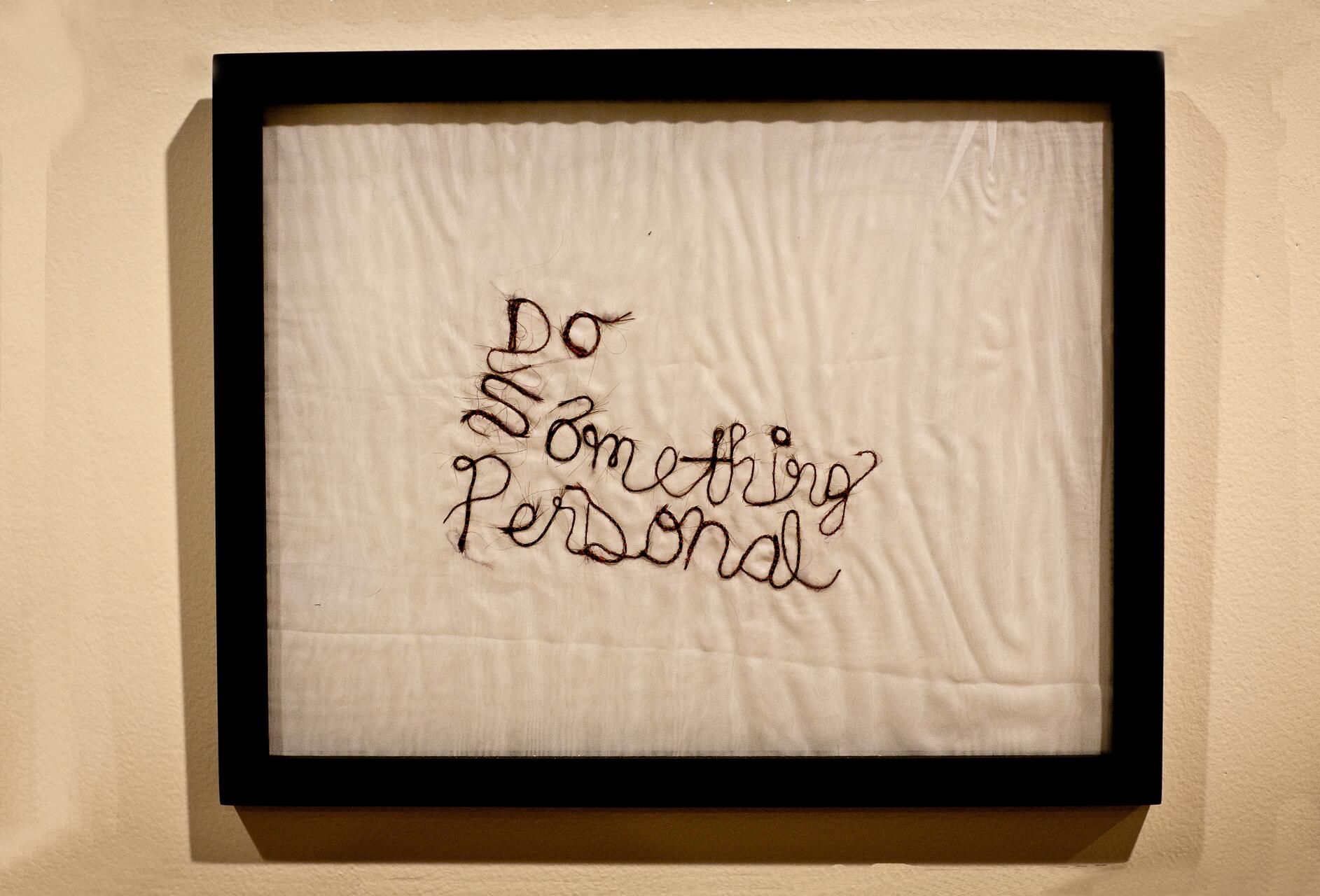 Embroidery art of cursive text "Do Something Personal" on white fabric, framed in black.