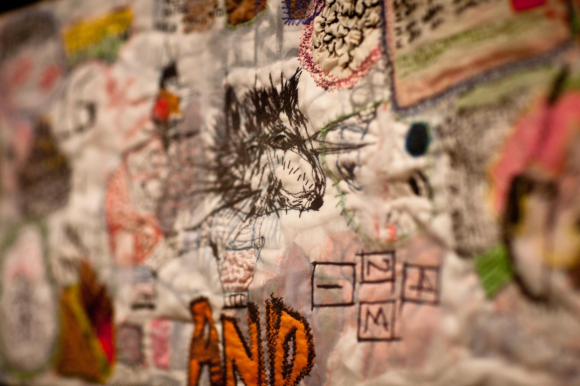 Abstract artwork with mixed media, featuring a drawn wolf's head, colorful patches, and embroidery. Various textures and colors blend in a collage-like manner.