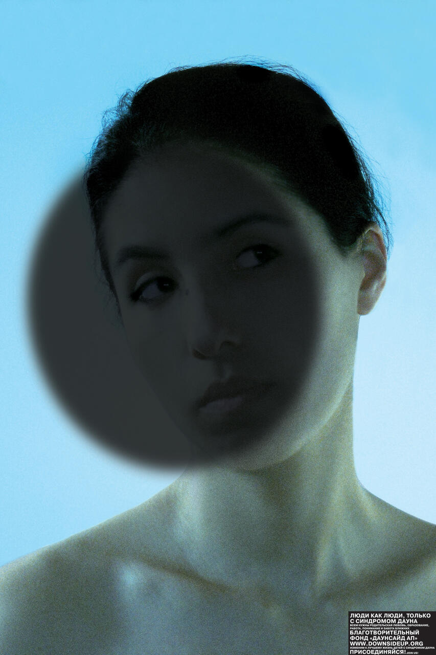 Person with dark circular shadow over face on a blue background.