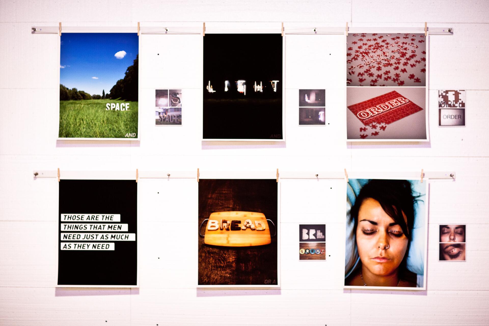A wall display of various artistic posters, including a landscape with "SPACE," a black print with glowing letters, puzzle pieces labeled "ORDER," and a large photo of a woman with closed eyes.