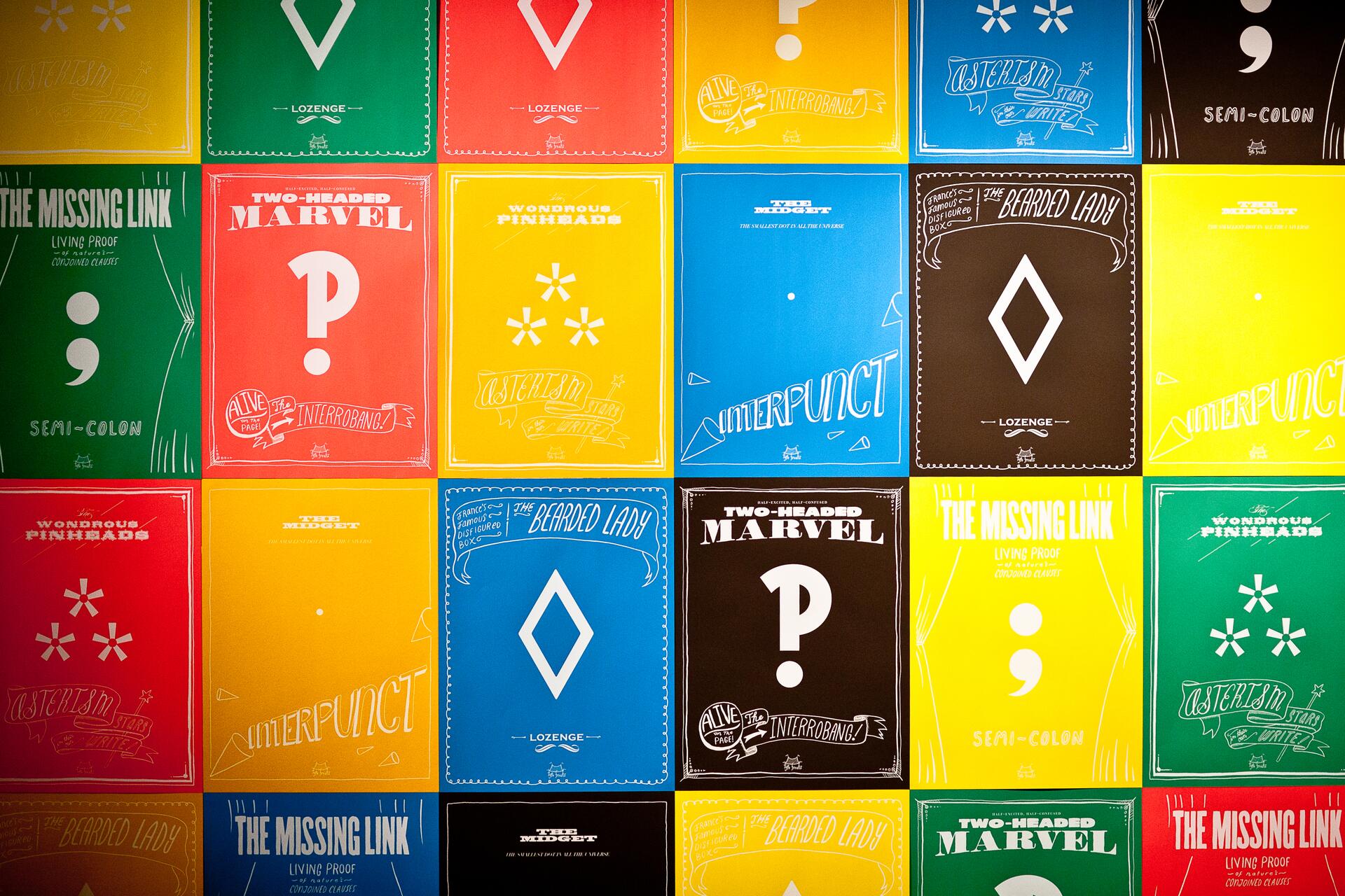 Colorful grid of posters featuring punctuation marks, each with playful text and graphic elements. The posters include various colors like red, yellow, blue, green, and black, with symbols such as question marks, semicolons, asterisks, and lozenges.