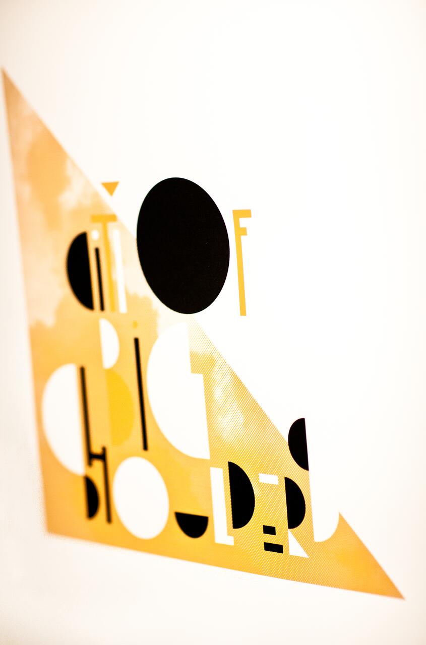 Abstract graphic with bold black and white geometric shapes and orange hues intersecting, creating stylized text partially visible.