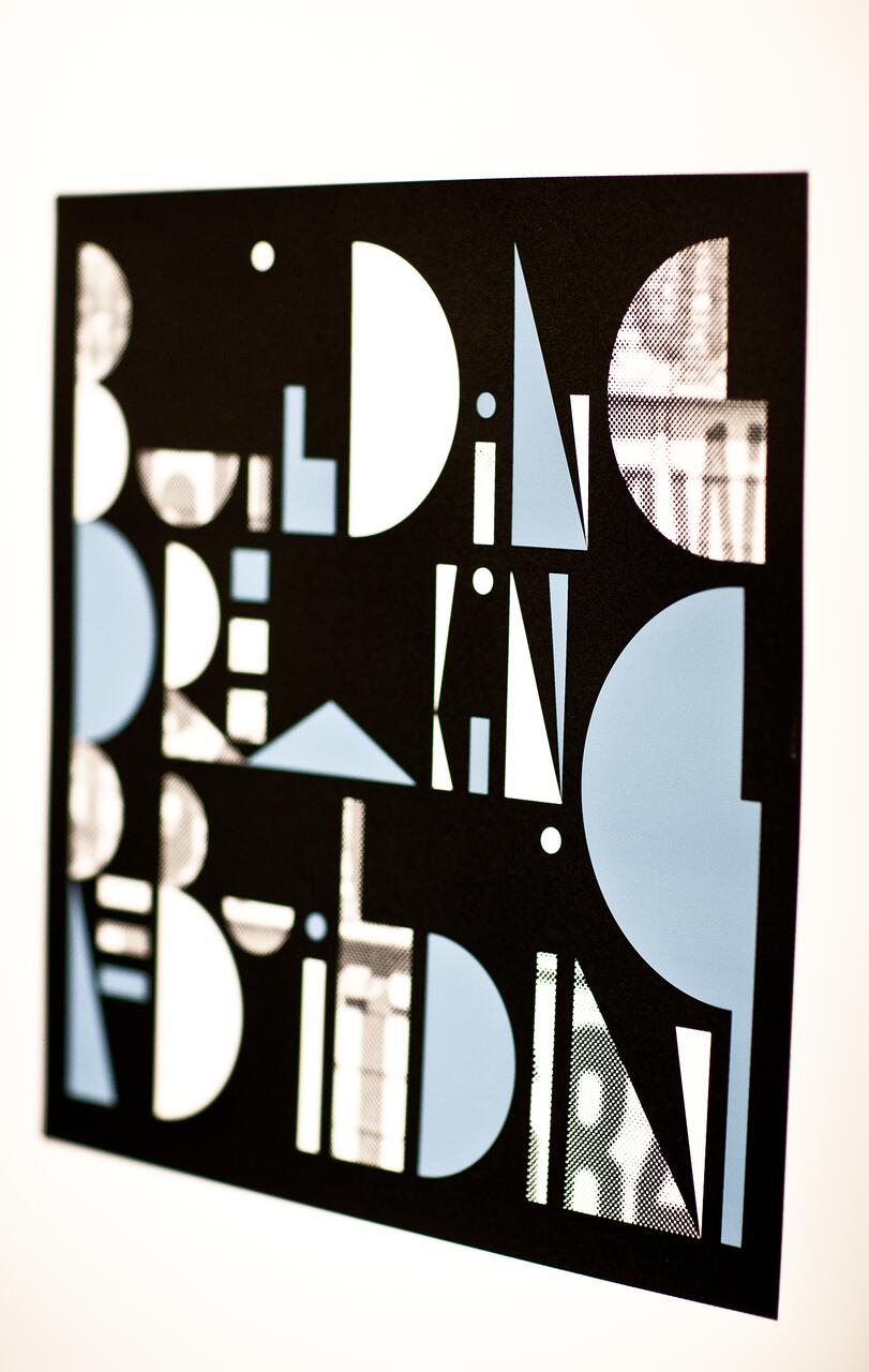 Black graphic design with cut-out letters overlaid on a background with blue and patterned textures.