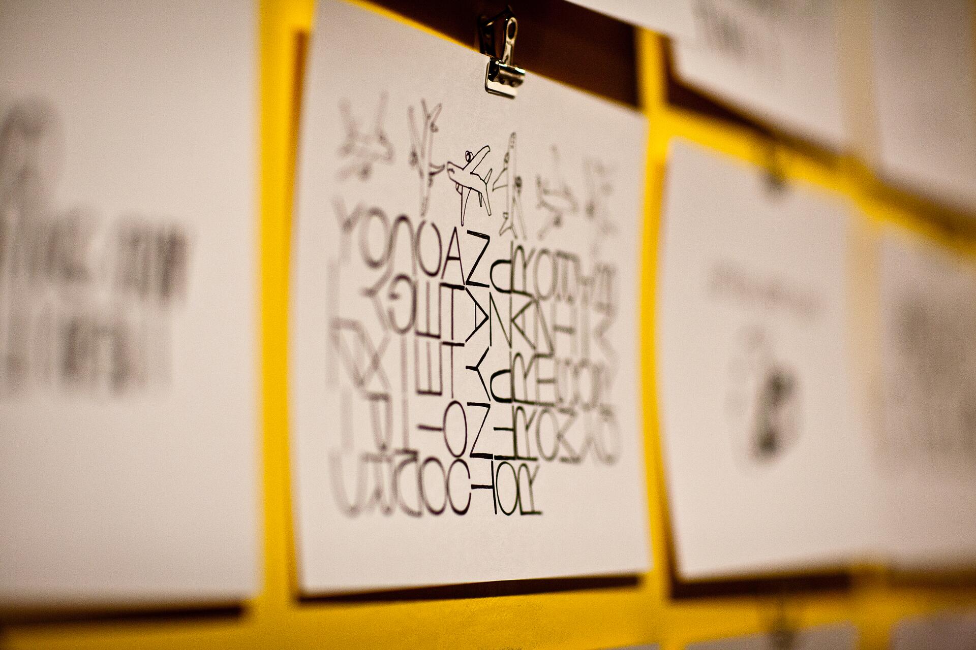Abstract design with airplanes and mixed letters on paper, clipped to a yellow background.
