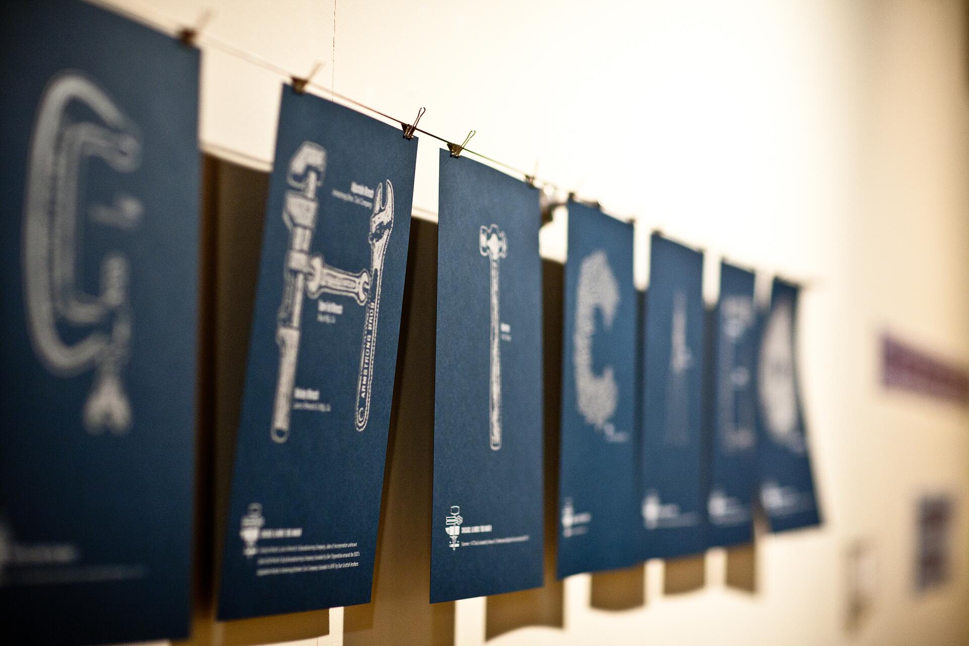Blue cards with white illustrations of tools hang on a line.