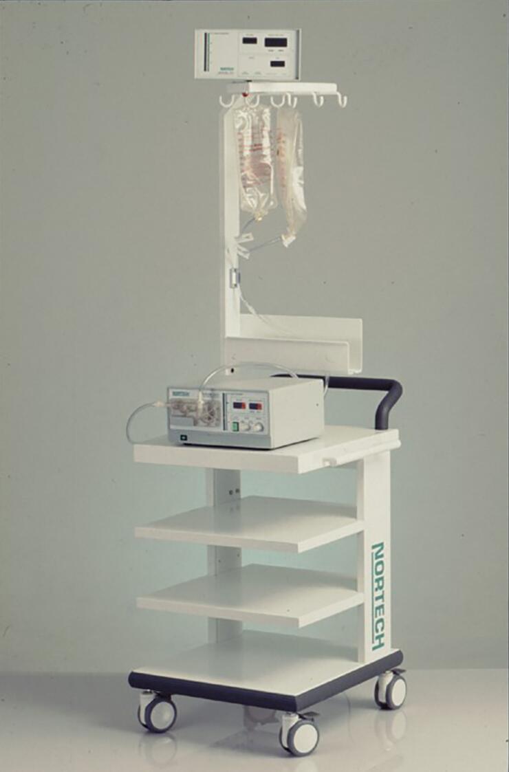 Medical equipment cart with IV bags, monitor, and pump. White shelves with a black handle and a rolling base.