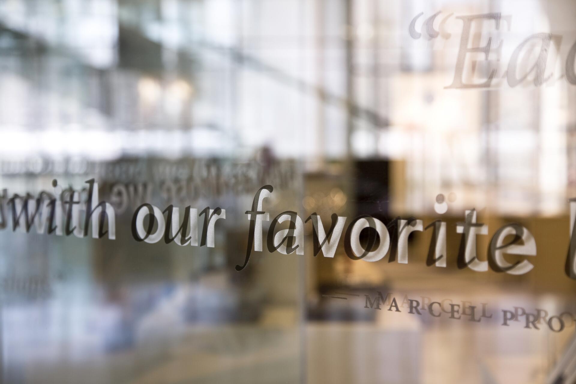 Text on glass reflecting a blurred office environment, with a phrase partially visible: "with our favorite."