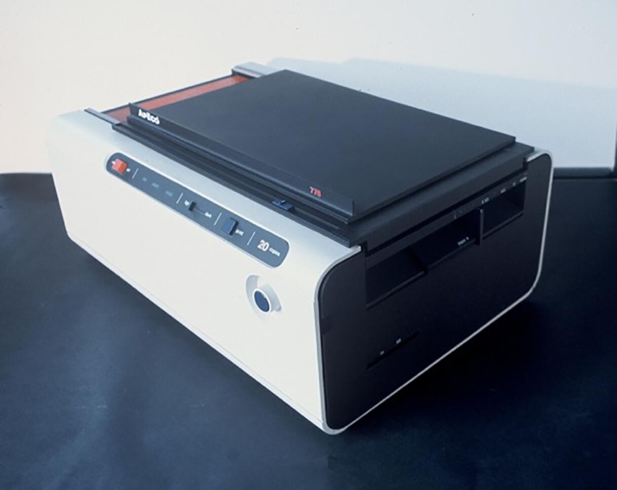 A sleek, rectangular scanner with a black top and white body, featuring a front panel with buttons and a slider.