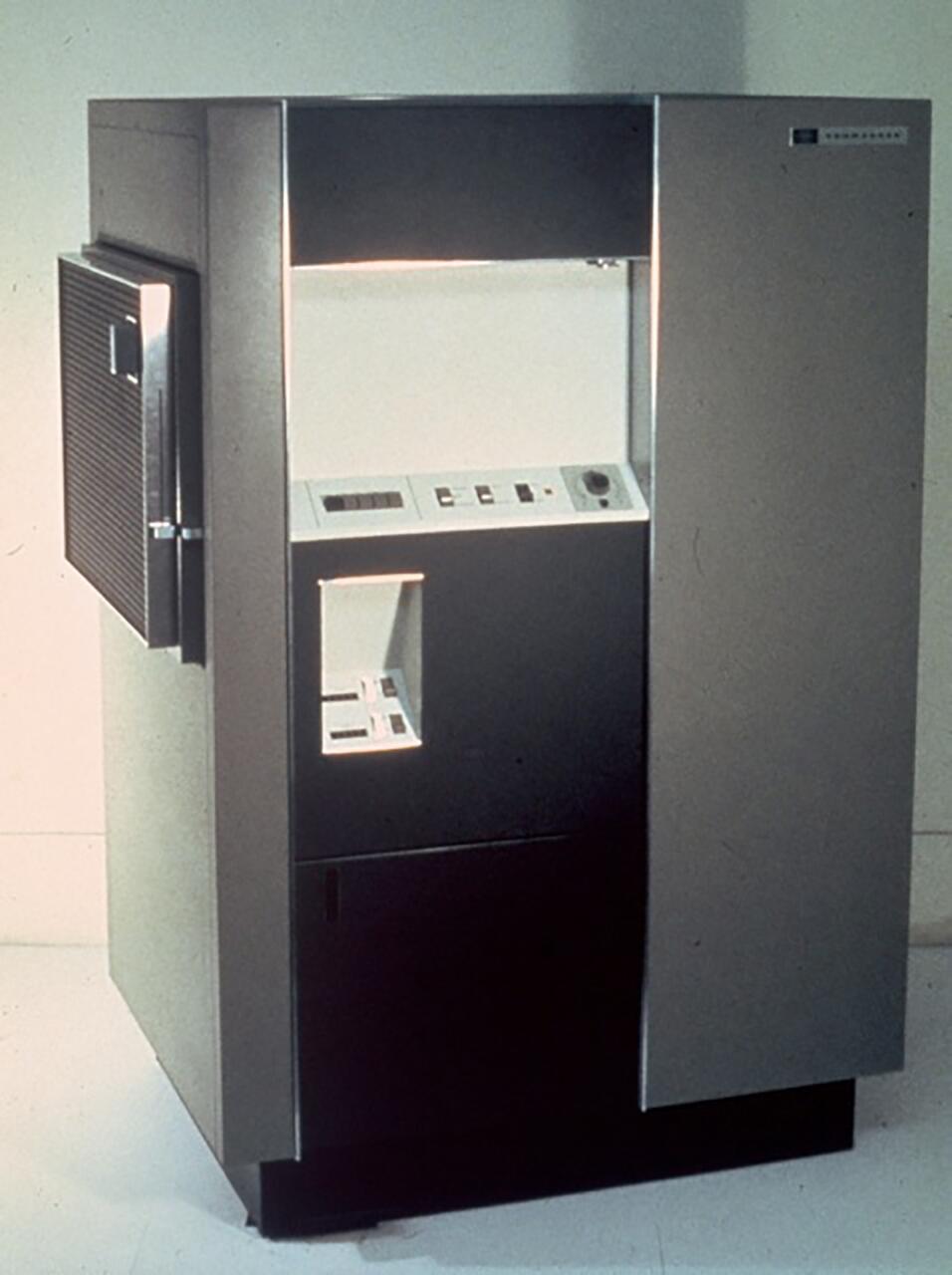 Large, vintage mainframe computer with a steel gray exterior, open front, and control panel featuring buttons, switches, and dials.