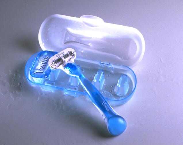 Blue Venus razor with Gillette branding in a matching plastic case, set on a wet surface.
