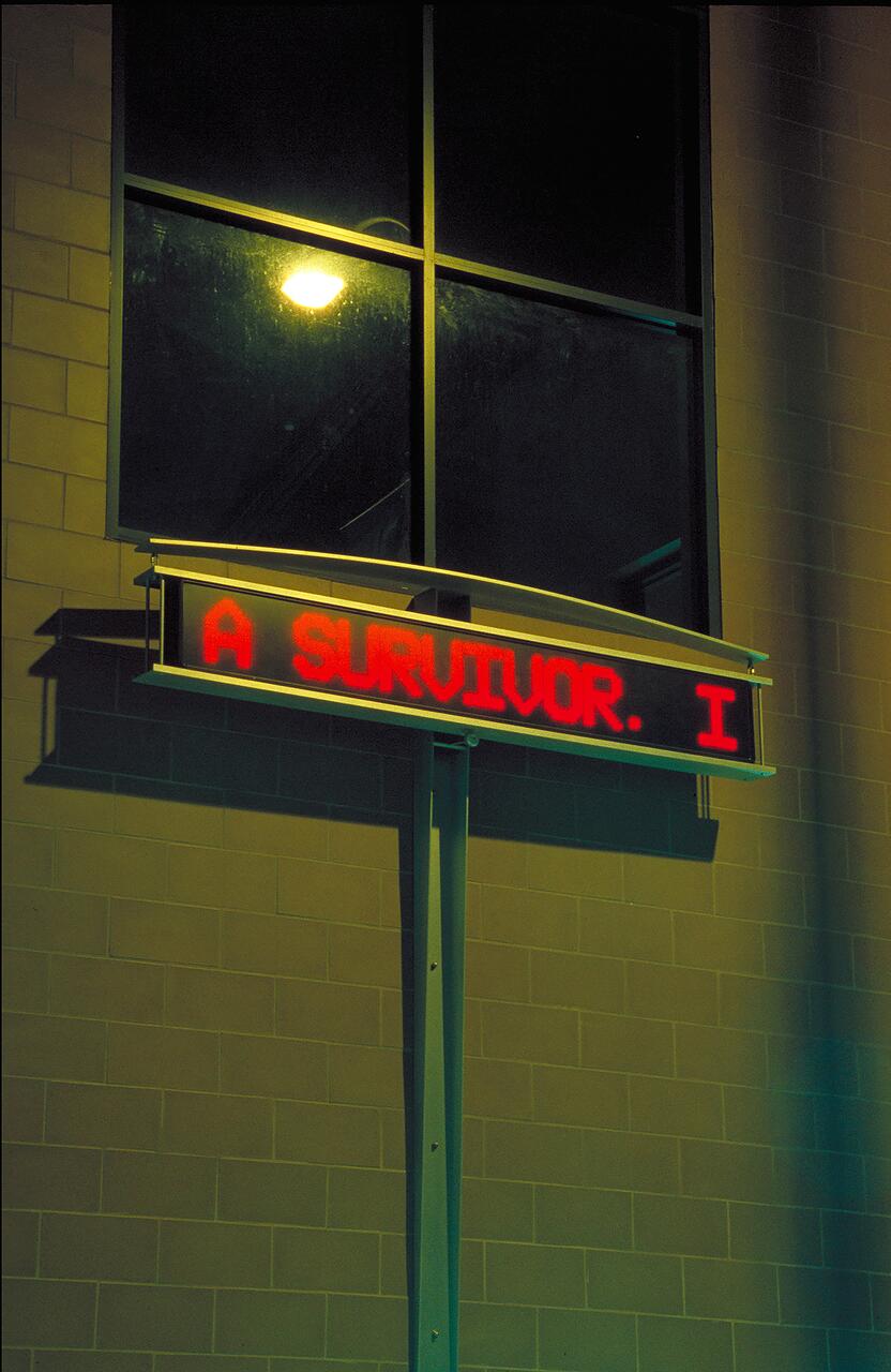 An electronic sign with red text hangs outside a building at night, reading, "A SURVIVOR." Dim lighting from a large window and a brick wall backdrop.