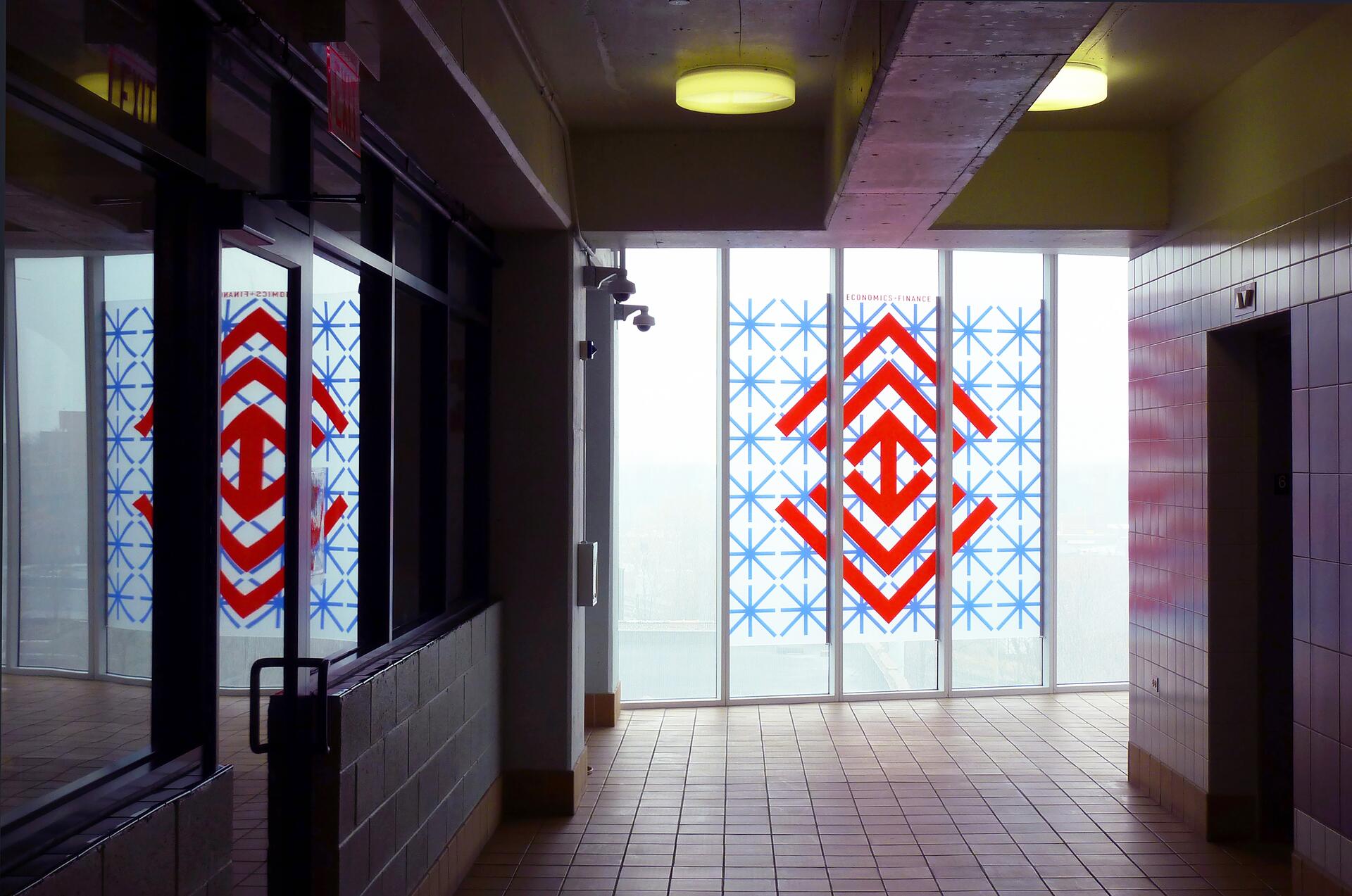 Hallway with large windows featuring geometric patterns in red and blue.