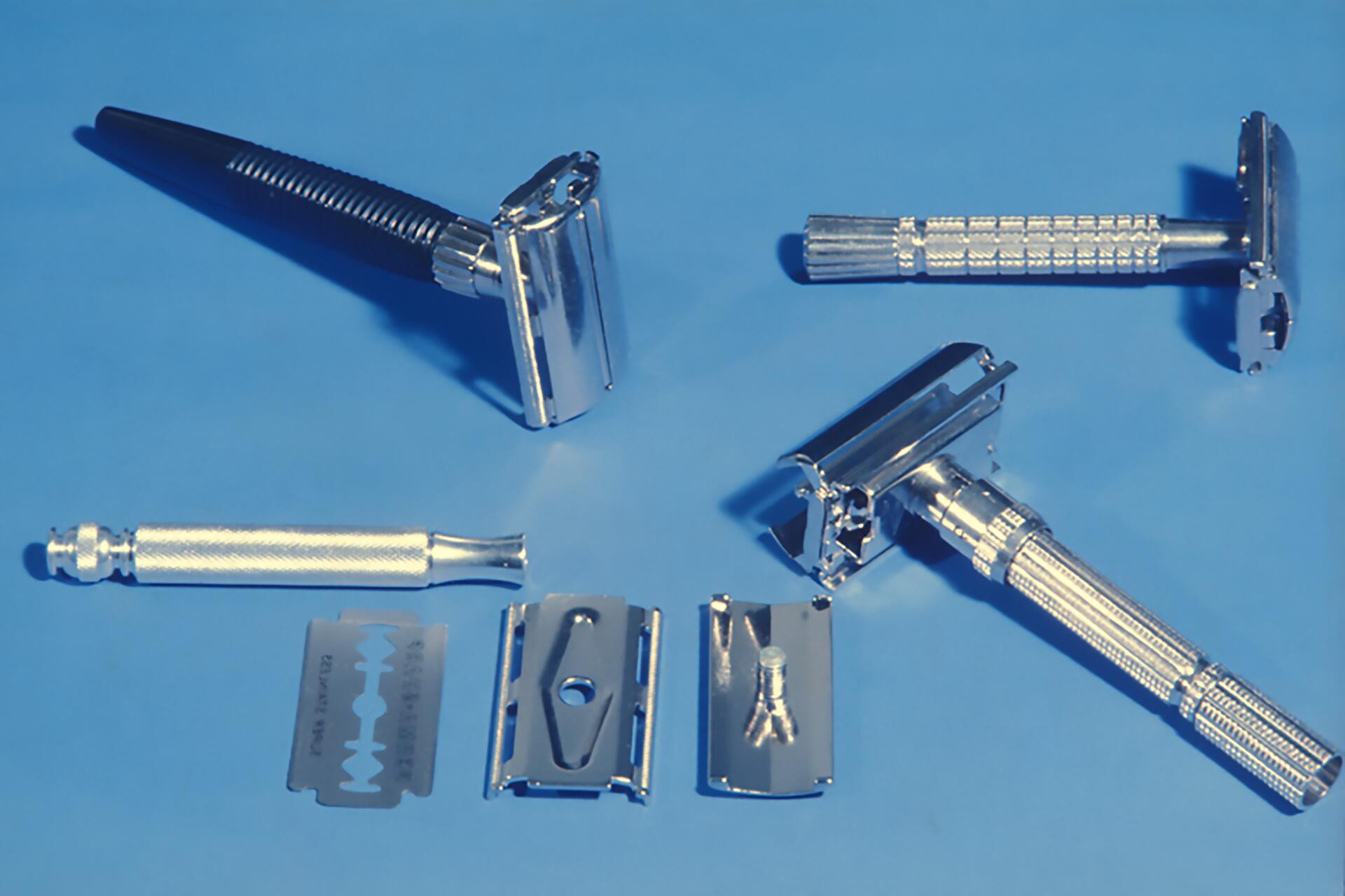 Assorted metal safety razors and blades arranged on a blue background.
