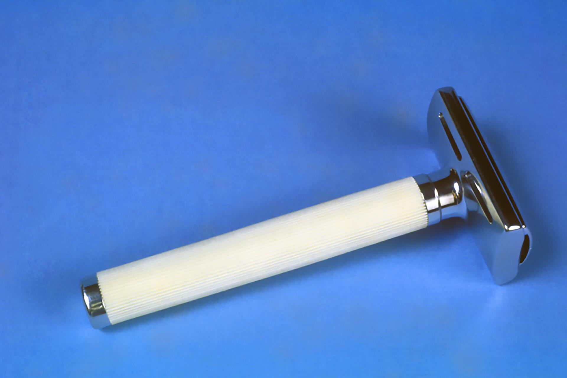 A safety razor with a ribbed white handle and shiny metal head, set against a blue background.