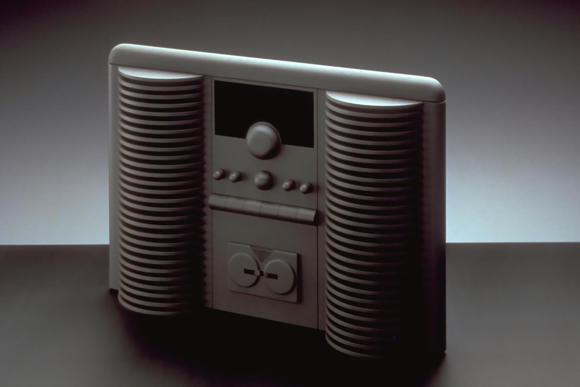 A sleek, retro stereo system with silver curved speakers and a central control panel featuring buttons and a knob, set against a gradient gray background.