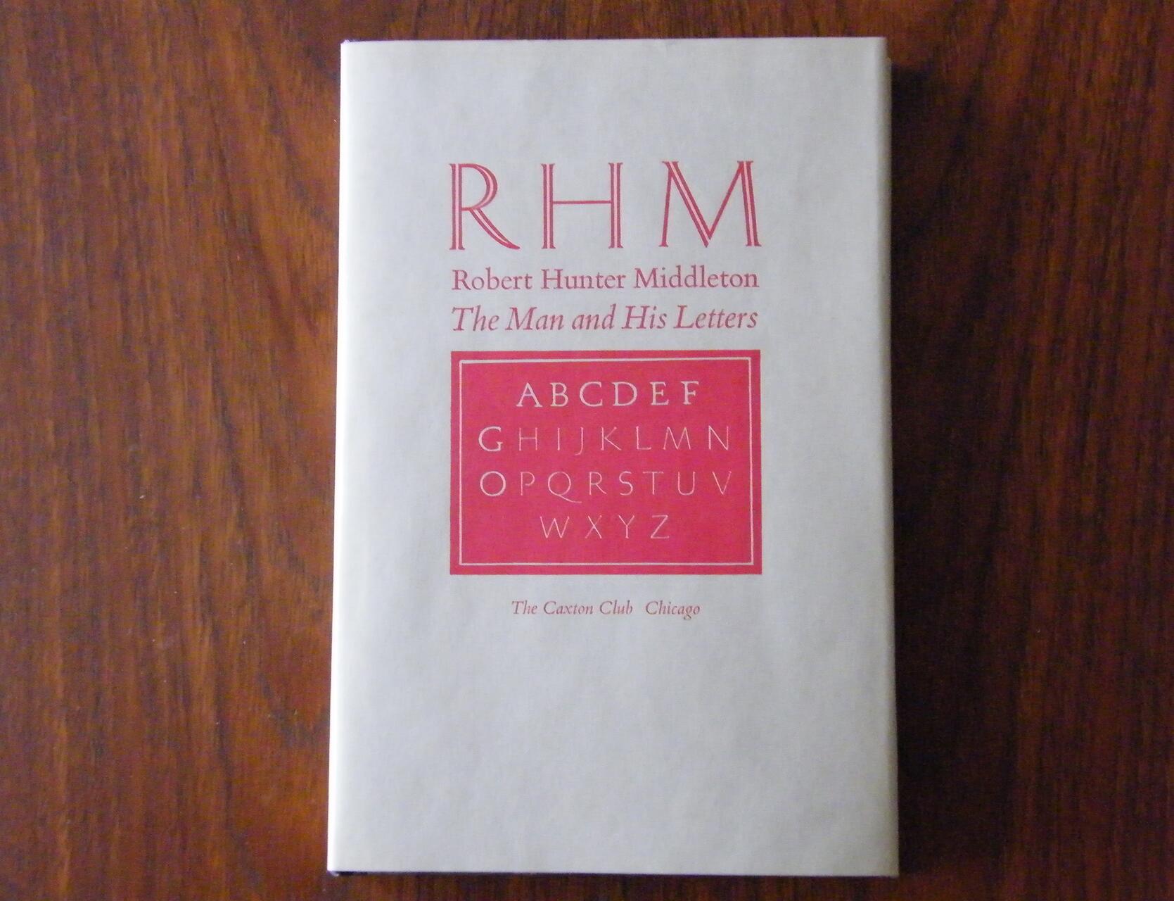 Cover of a book titled "RHM Robert Hunter Middleton: The Man and His Letters," featuring red text on a beige background with the alphabet in a red square beneath the title. Placed on a wooden surface.