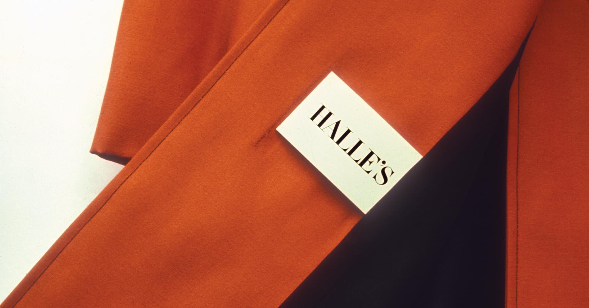 Orange fabric with a white tag labeled "HALLE'S" pinned to it.