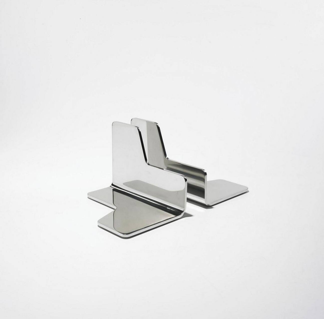 A pair of glossy, metallic bookends on a white background, featuring a modern, angular design with a reflective surface.