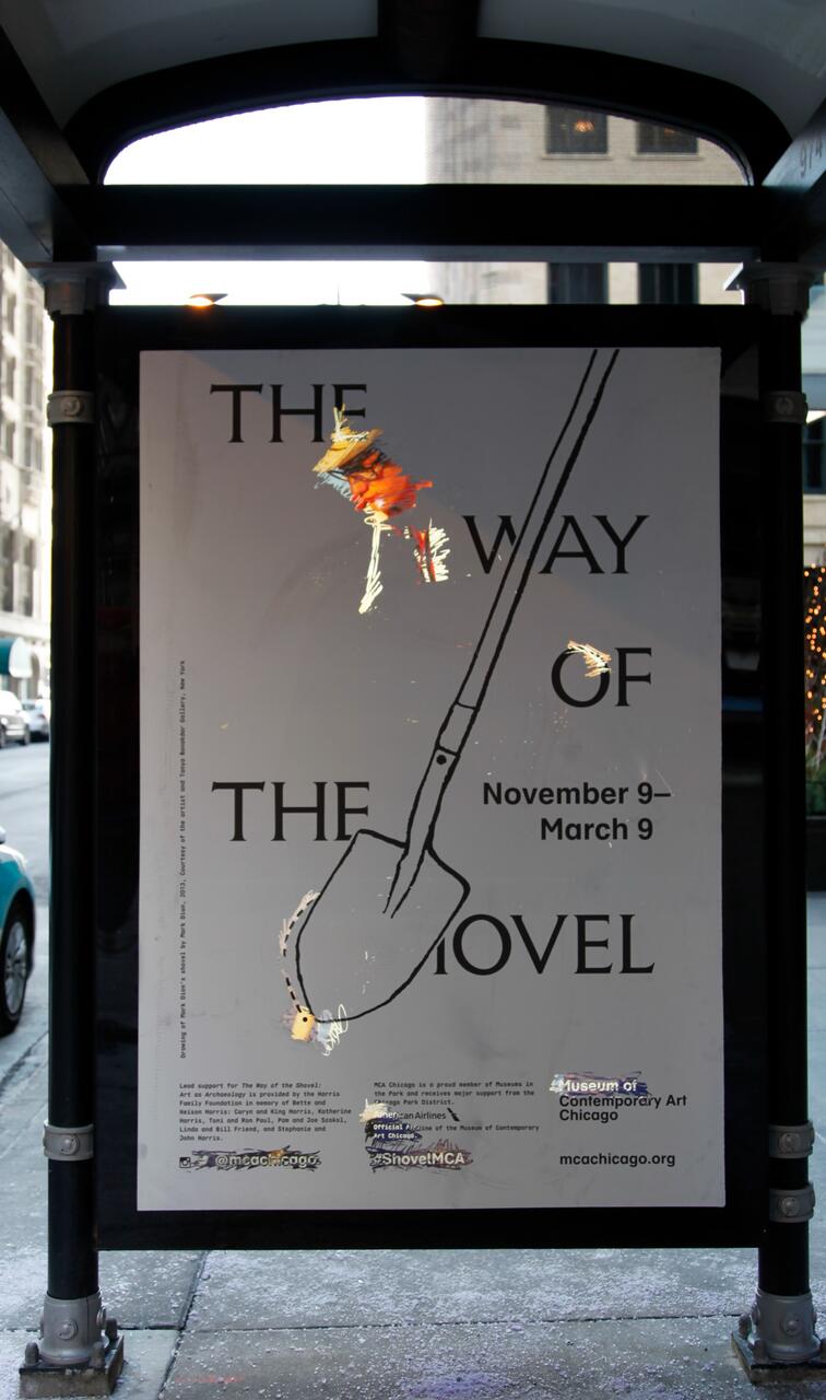 Bus stop advertisement with a shovel illustration, text including "The Way of the Shovel," and event dates "November 9 – March 9." Background shows an urban street with buildings and vehicles.