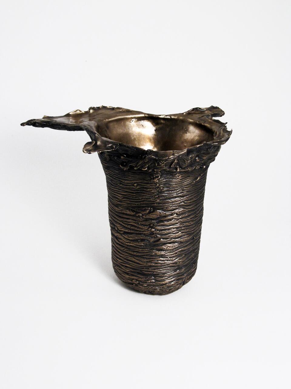 Bronze sculpture resembling a textured, cylindrical vessel with a rugged, wavy rim, displaying rich metallic tones against a plain white background.