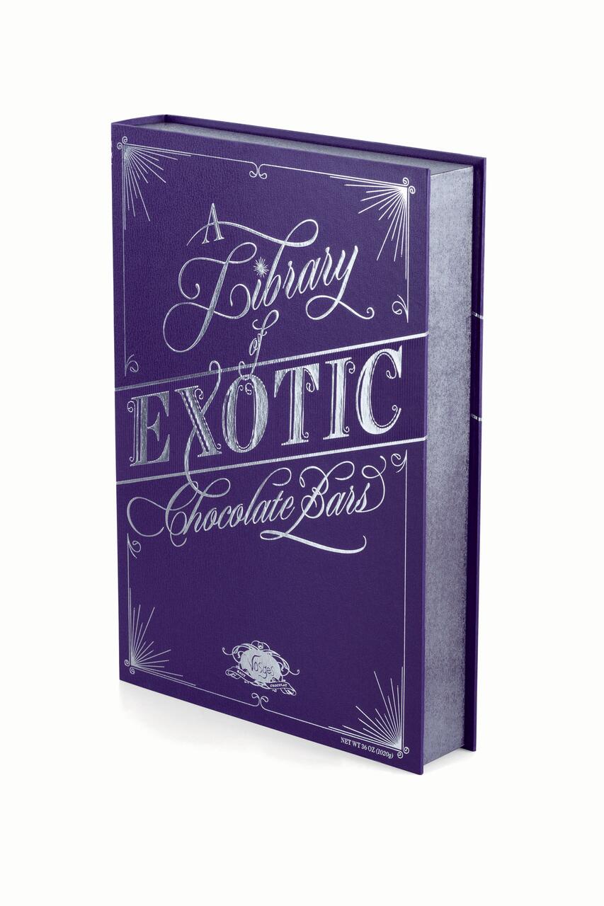Purple book-shaped box with ornate silver lettering reading "A Library of Exotic Chocolate Bars," surrounded by decorative elements.