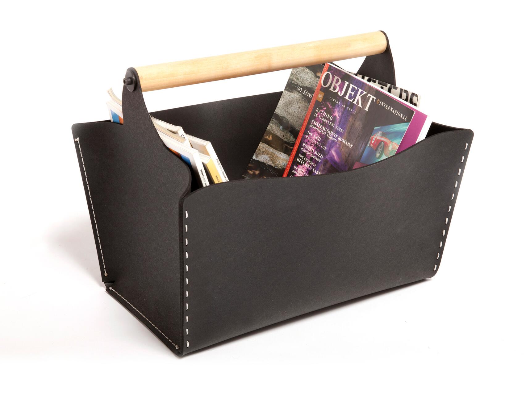 Black leather magazine holder with a wooden handle, containing several colorful magazines.