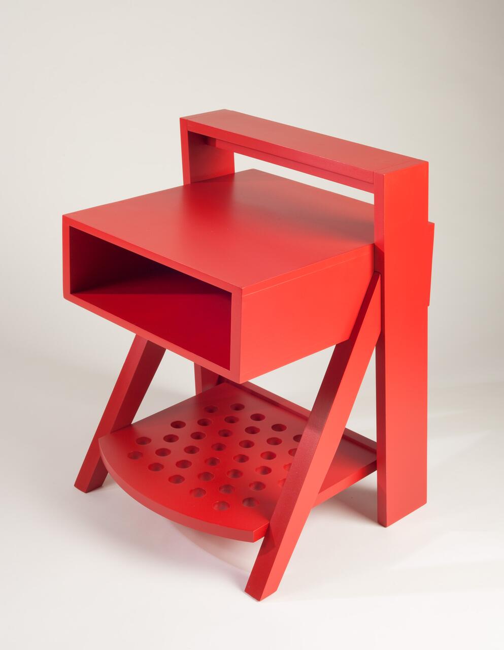 Red geometric chair with a rectangular seat, a hollow backrest, and a perforated semicircular base.
