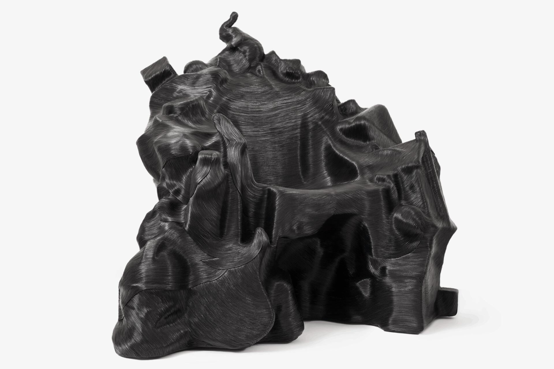 Black abstract sculpture with a twisted, organic form and smooth textures, resembling flowing fabric or rock formations.