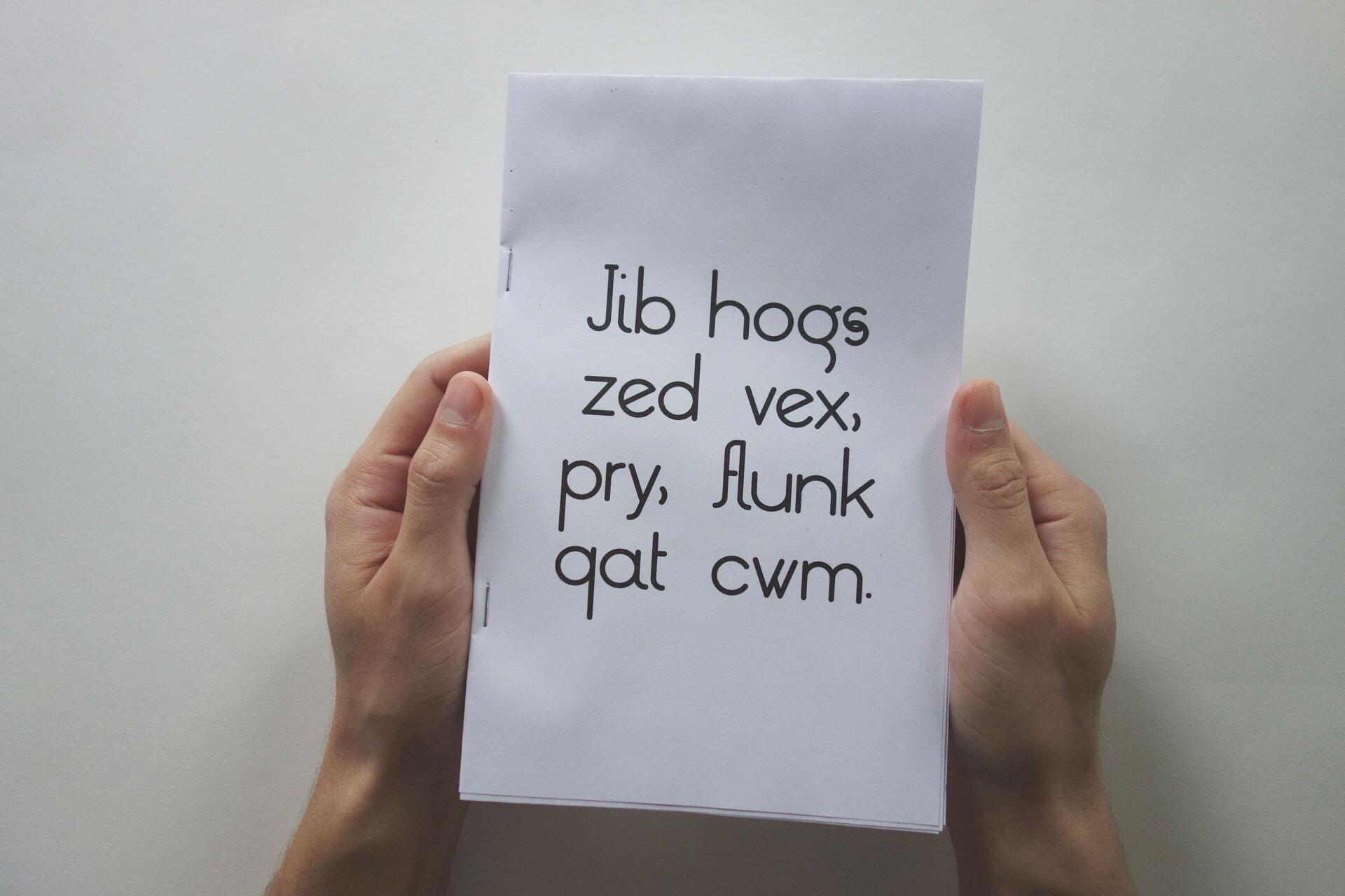 Hands holding a booklet with nonsensical text on the cover.