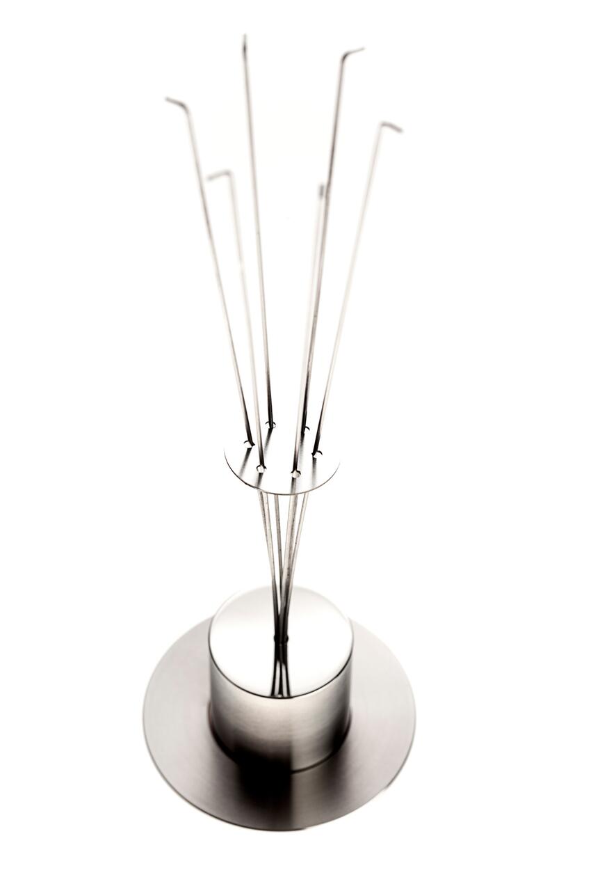 Chrome metal sculpture with long, upward-curving rods, mounted on a circular base against a white background.