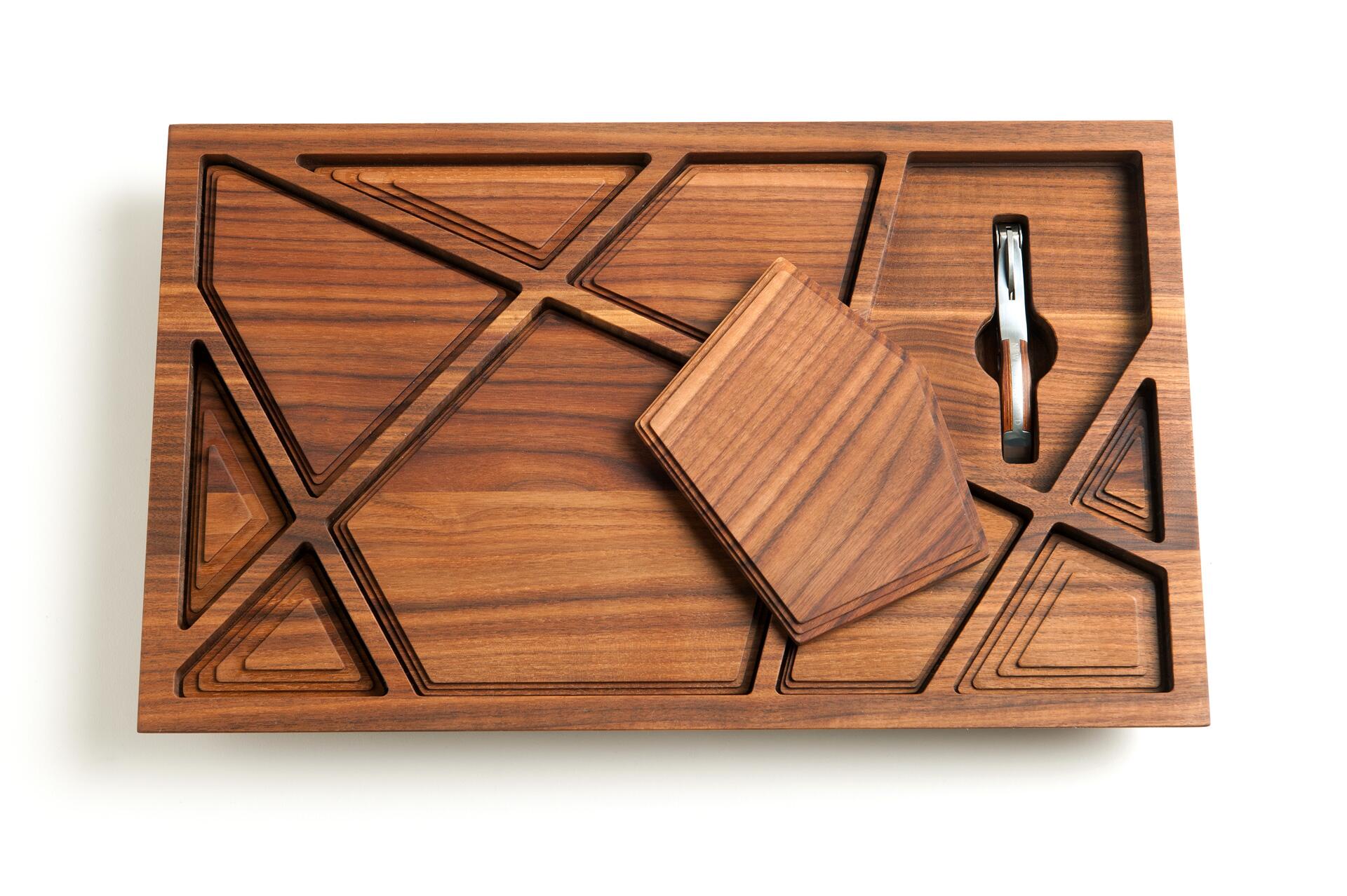 Wooden puzzle board with geometric shapes and a slot holding a metallic tool.