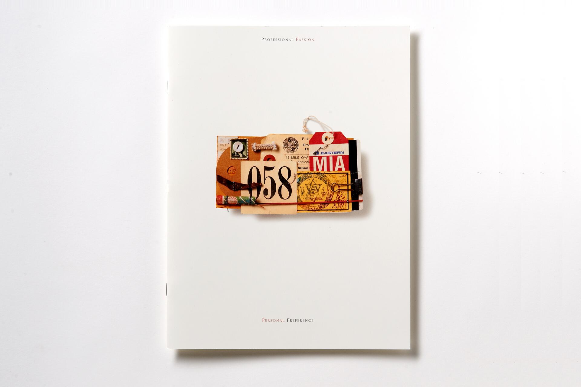 A collage with vintage travel tags and tickets is attached to a white booklet with faint text.