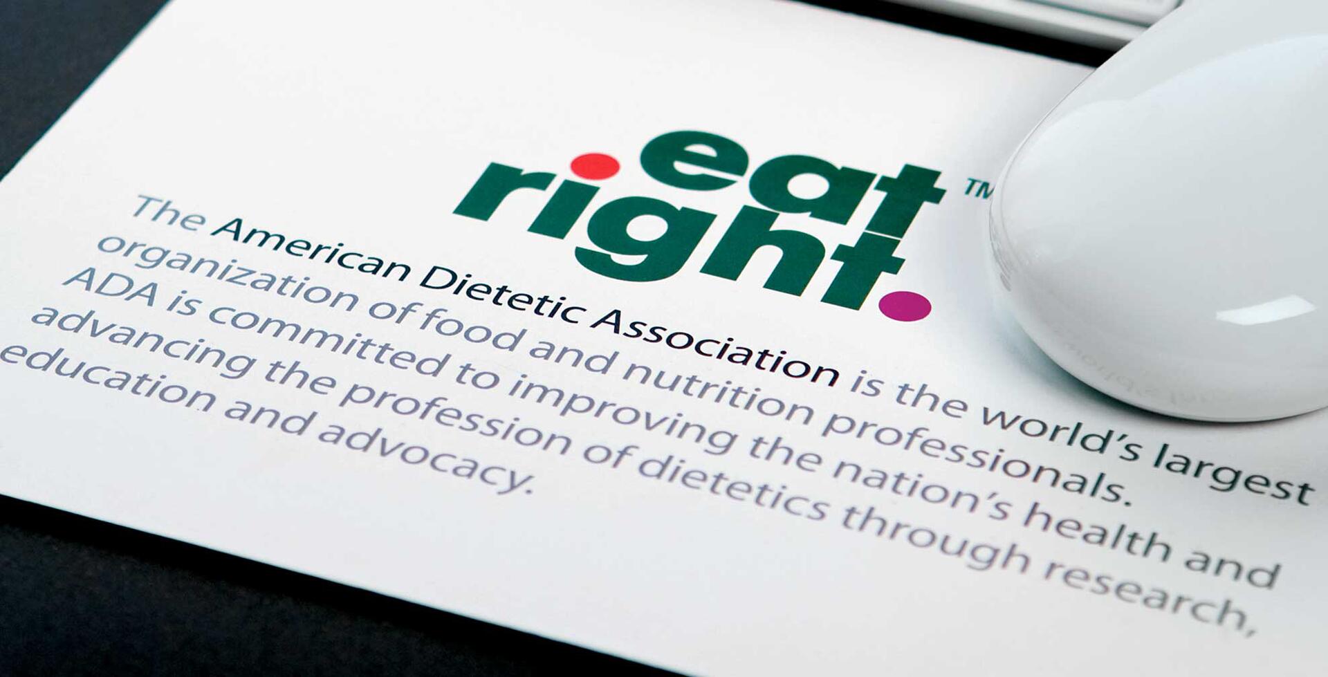 Text reading "eat right" in bold with a dot design, above a description of the American Dietetic Association's mission, partially covered by a white computer mouse.