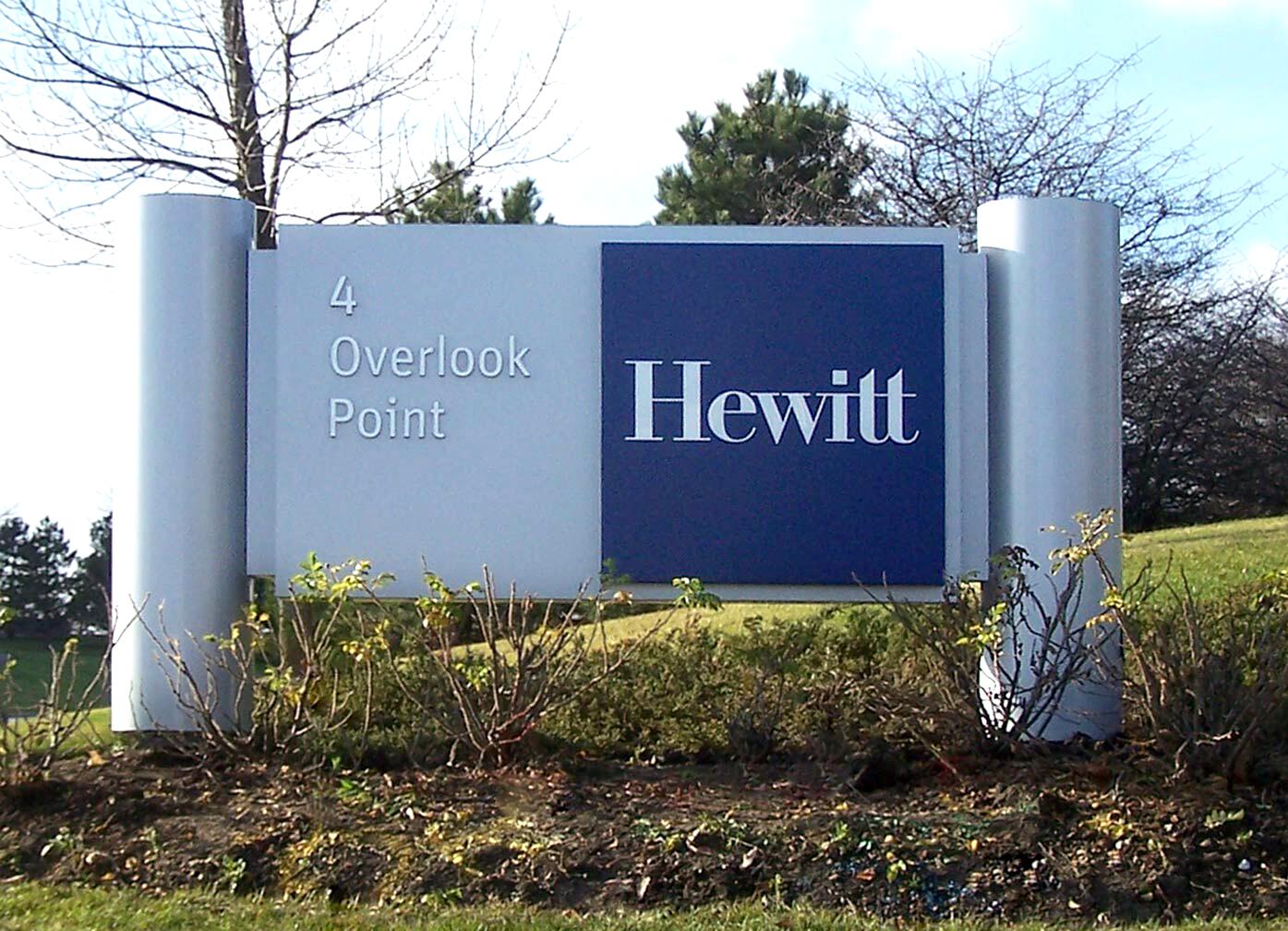 Signboard reading "4 Overlook Point" with a large blue square displaying "Hewitt," set in a landscaped area with grass and bushes.