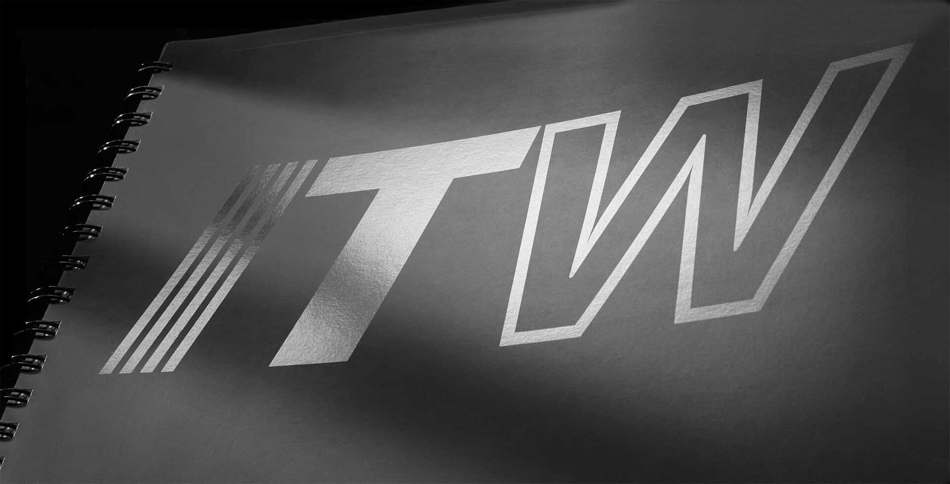 Spiral-bound notebook with metallic letters "ITW" embossed on the cover in a sleek, black and white design.