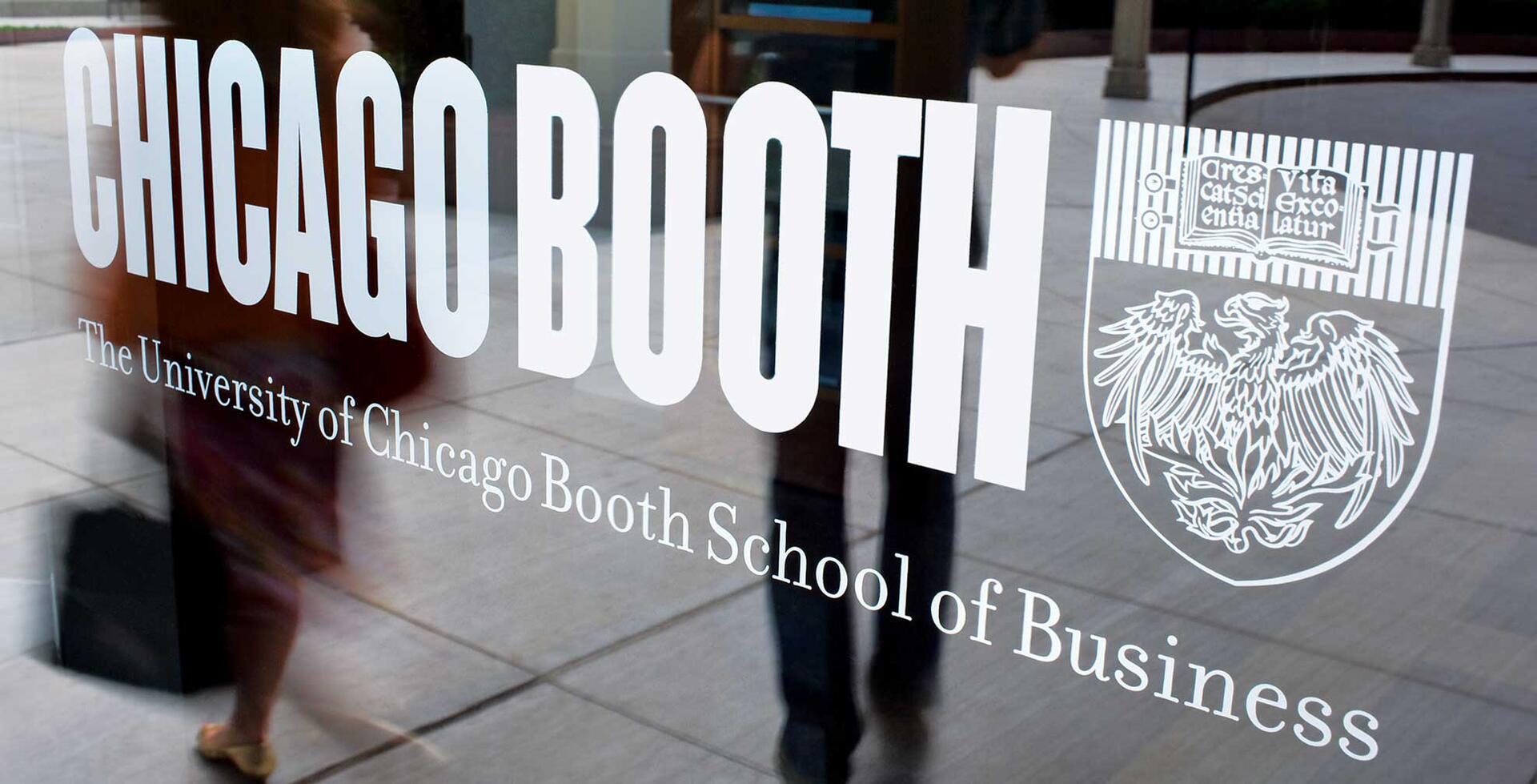 Glass door with "Chicago Booth, The University of Chicago Booth School of Business" and the school's crest, reflecting blurred figures walking past.