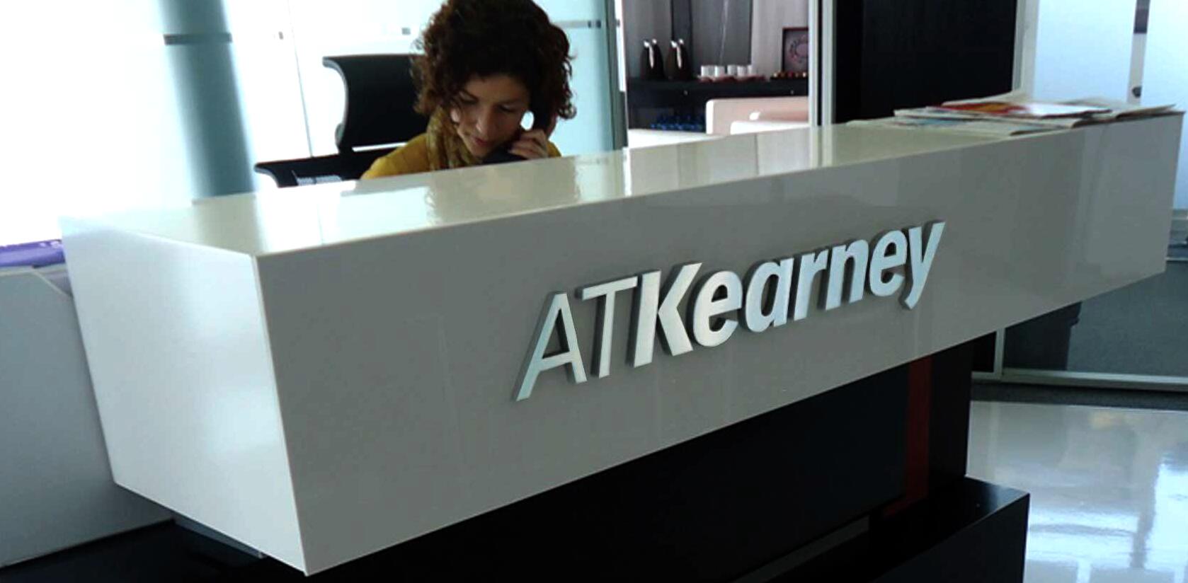Reception desk with AT Kearney logo, featuring a person on the phone behind it.