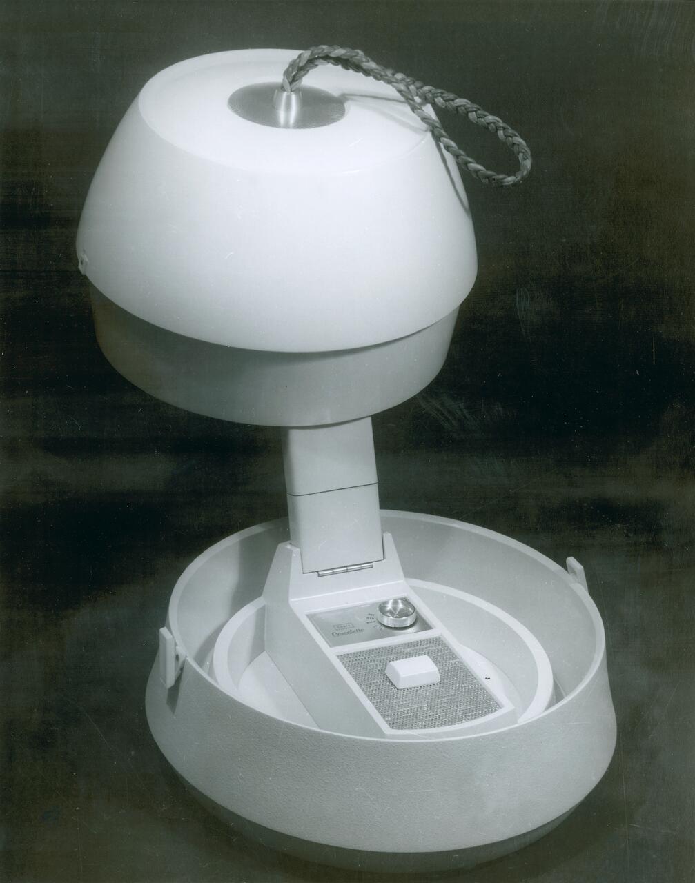 Retro-style intercom with a dome-shaped top and braided cord, displaying a speaker and control button panel, set in a studio-like environment with grayscale tones.
