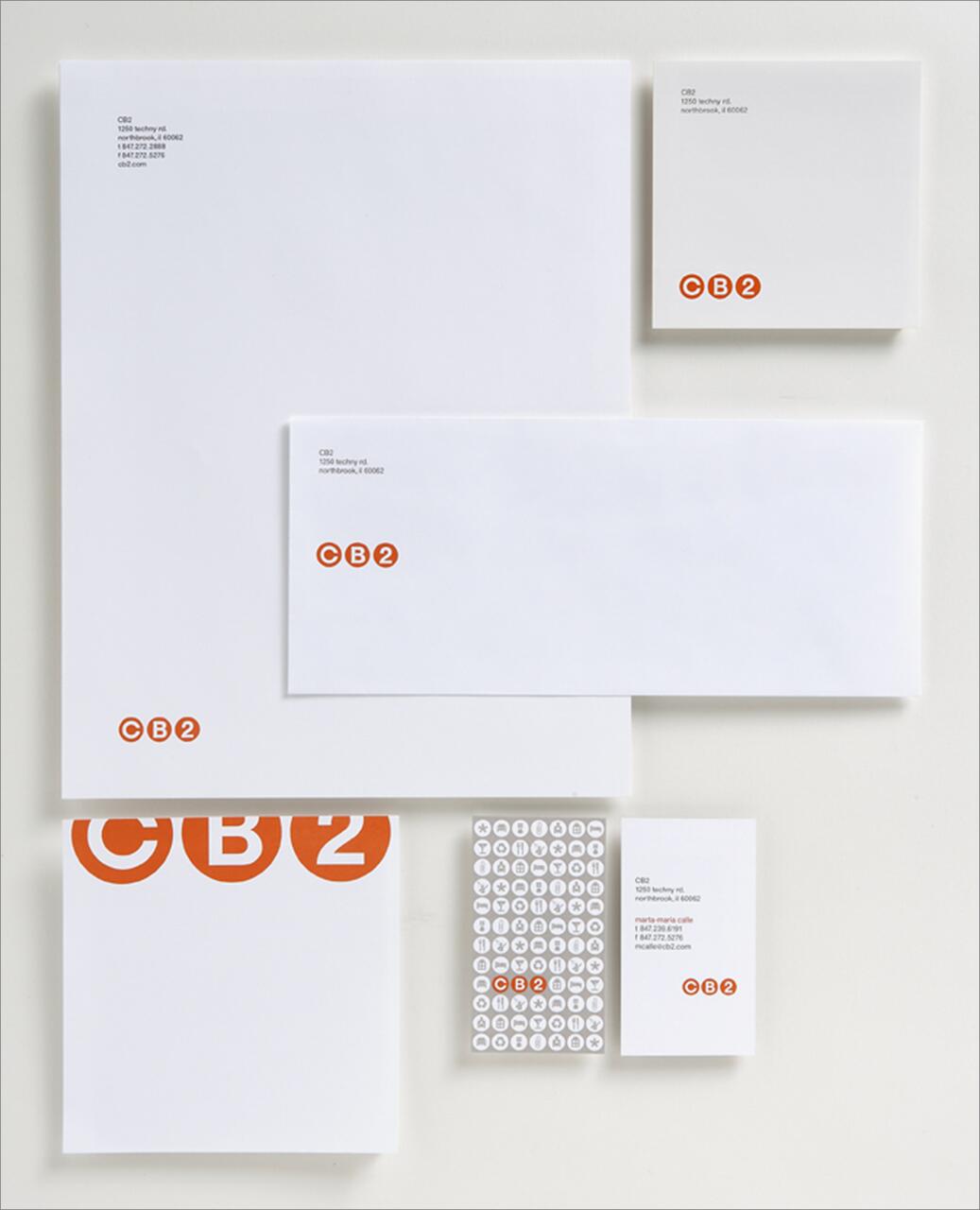 Stationery set with CB2 branding, featuring business cards, envelopes, letterheads, and logo stickers in white and orange.