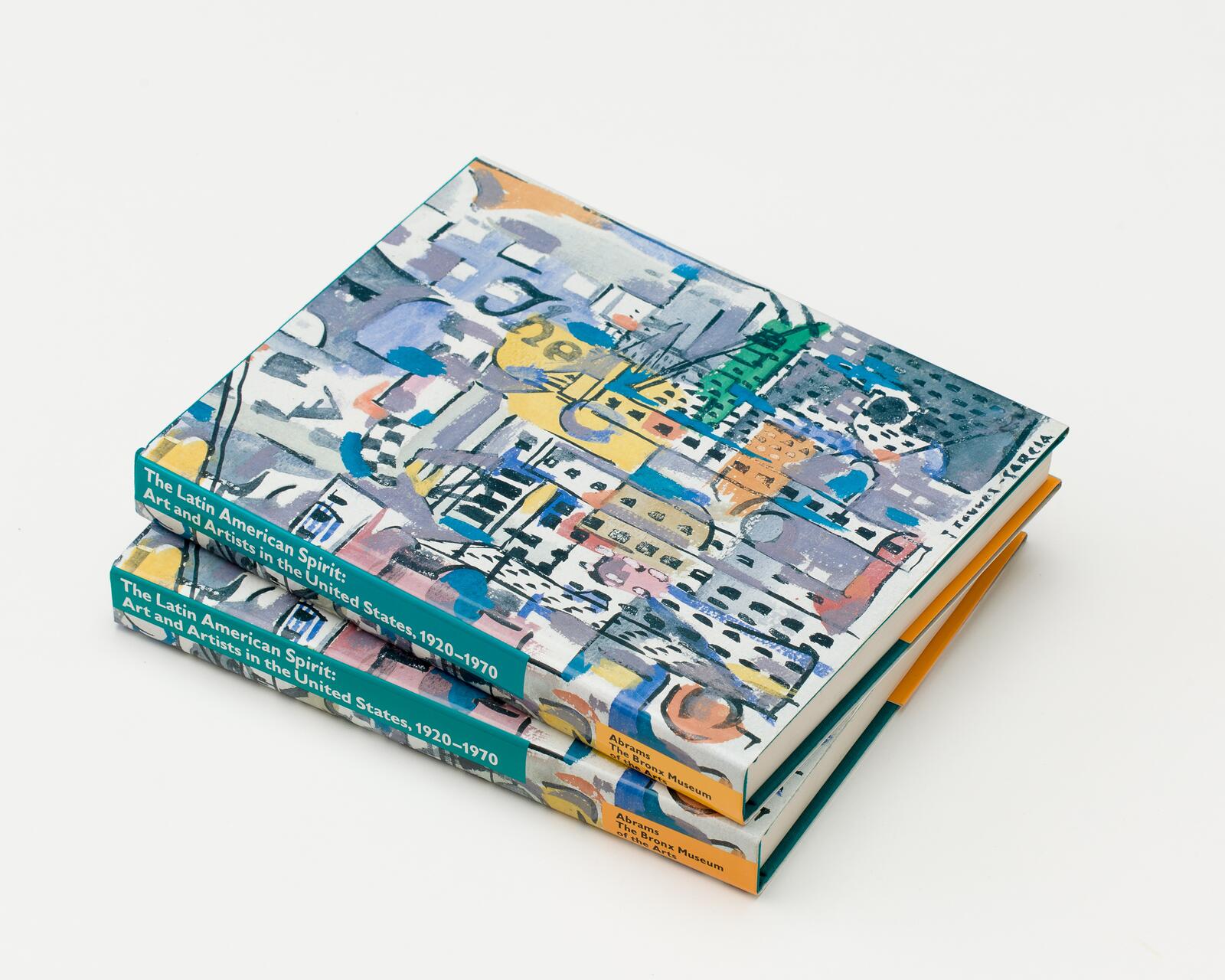 Stacked hardcover books titled "The Latin American Spirit: Art and Artists in the United States, 1920-1970" with colorful, abstract covers featuring urban artwork.