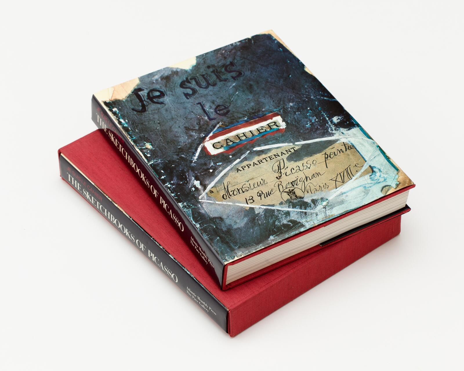 Two hardcover books with red spines, titled "The Sketchbooks of Picasso," stacked on a white background. The top book has an artistic cover with handwritten notes and abstract design.