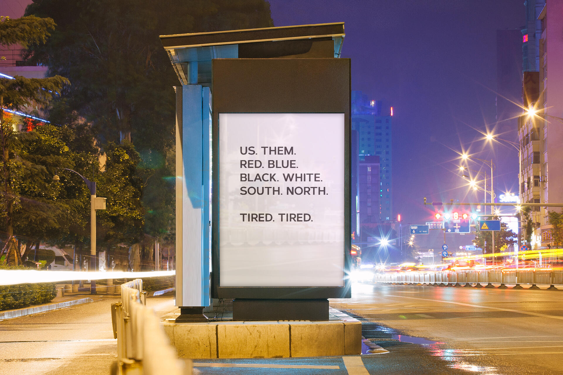An illuminated billboard in a city at night with blurred car lights on the street.