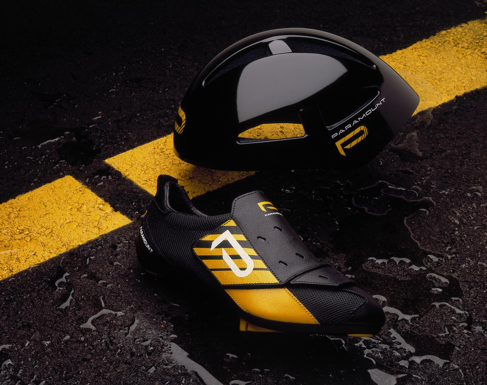 Black and yellow cycling shoe and helmet on wet asphalt with a yellow line.