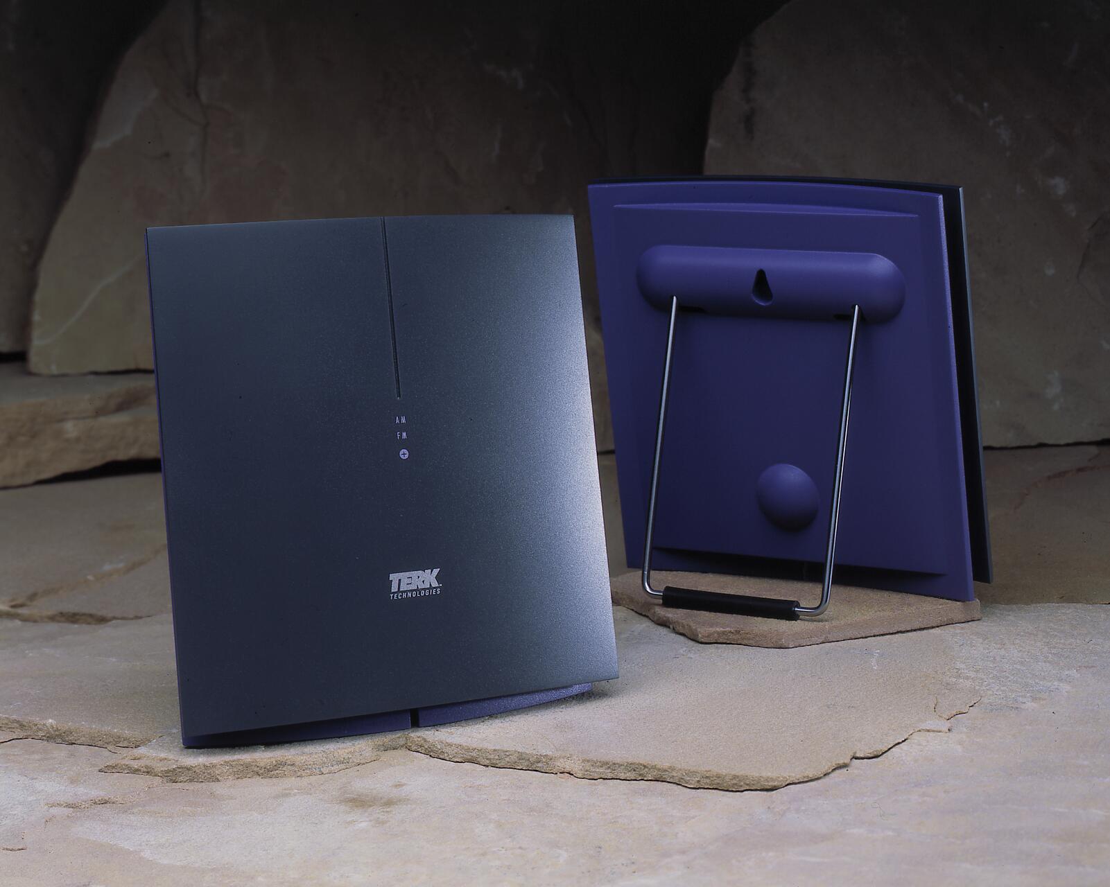 Black and purple television antennas with sleek design, standing on a stone surface. The front panel displays "TERK Technologies." The background features large rocks.