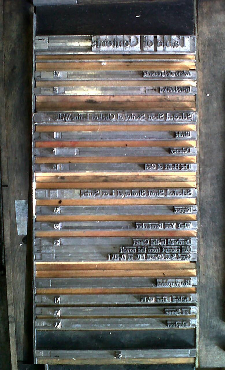 Wooden letterpress typeset arranged in a printer's tray, viewed from above.