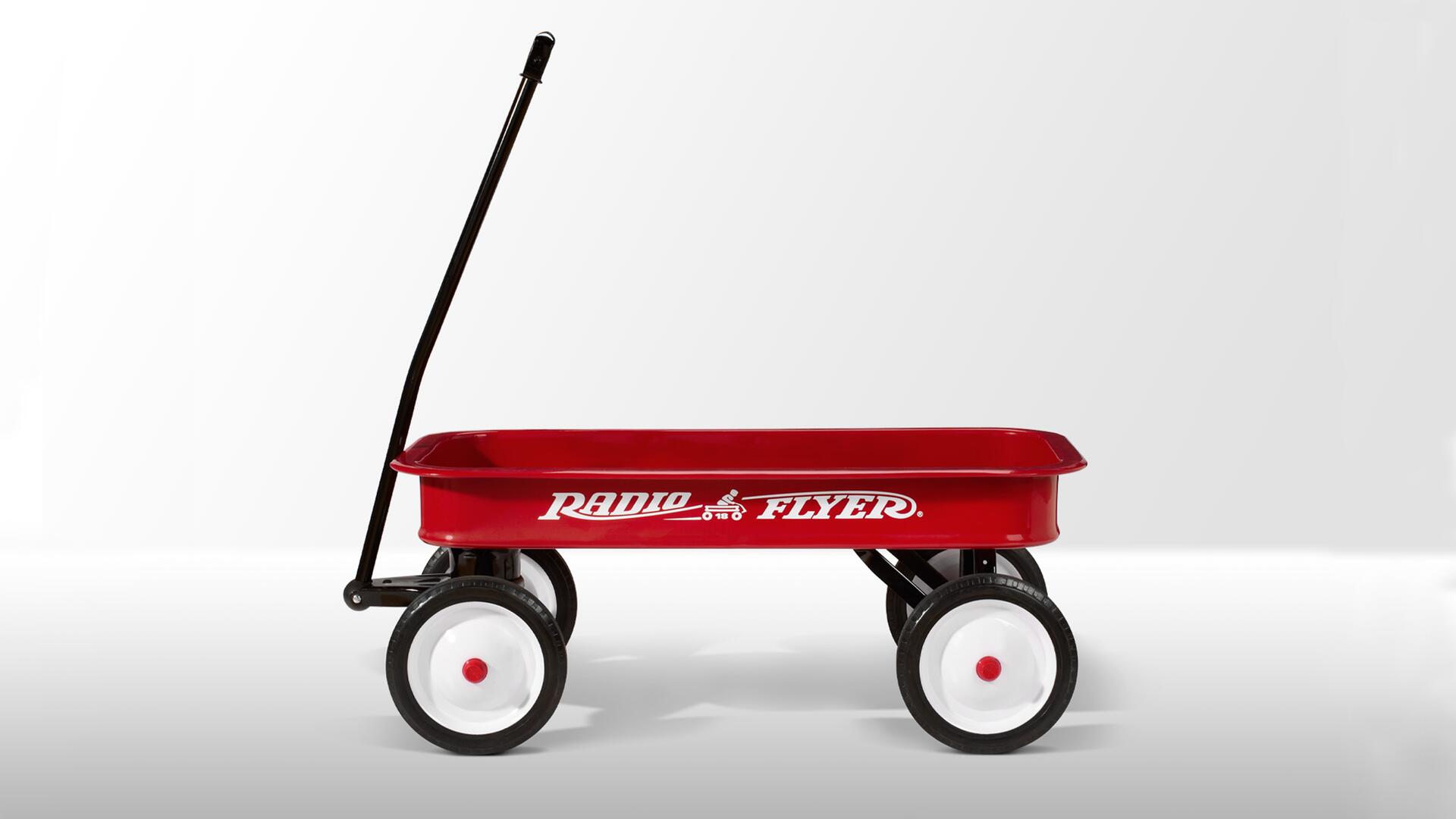 Red toy wagon with a long black handle and white wheels, displayed against a light gray background.