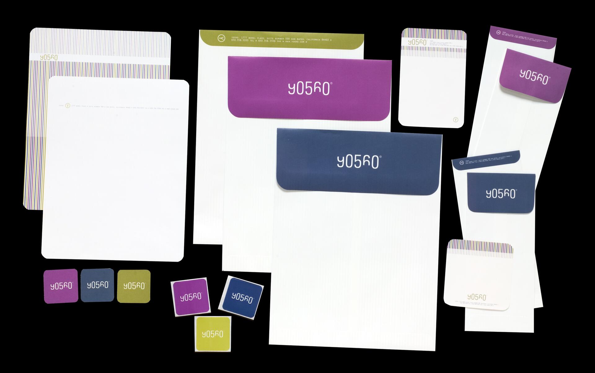 Stationery set with colorful envelopes and stickers featuring a stylized logo on a black background. Includes large and small envelopes with vibrant flap colors in purple, blue, and olive, accompanied by matching square stickers.
