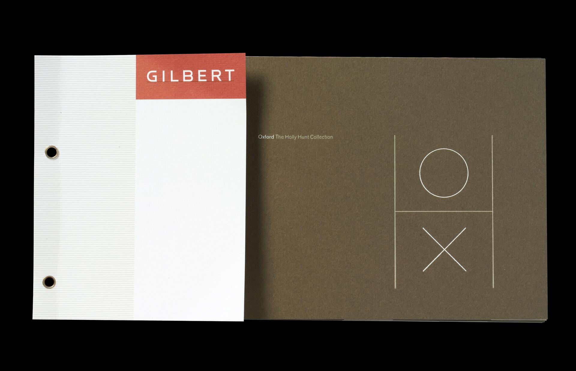 Two binder covers, one white with a red header labeled "GILBERT," and another brown featuring minimalist tic-tac-toe graphics with a circle and an "X."