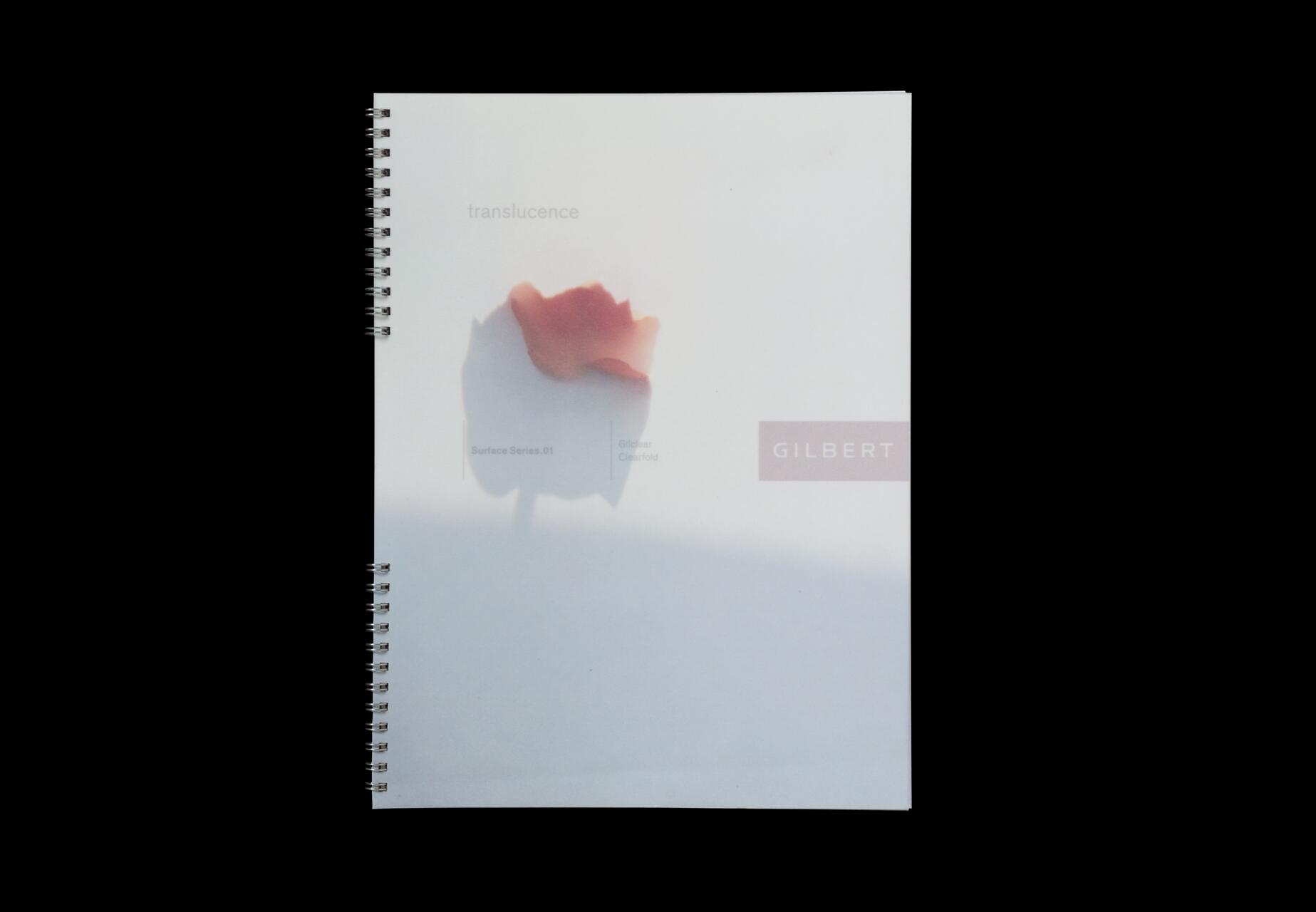 Spiral-bound notebook with a soft-focus image of a red flower on a white background, featuring the word "GILBERT" in a pink box.