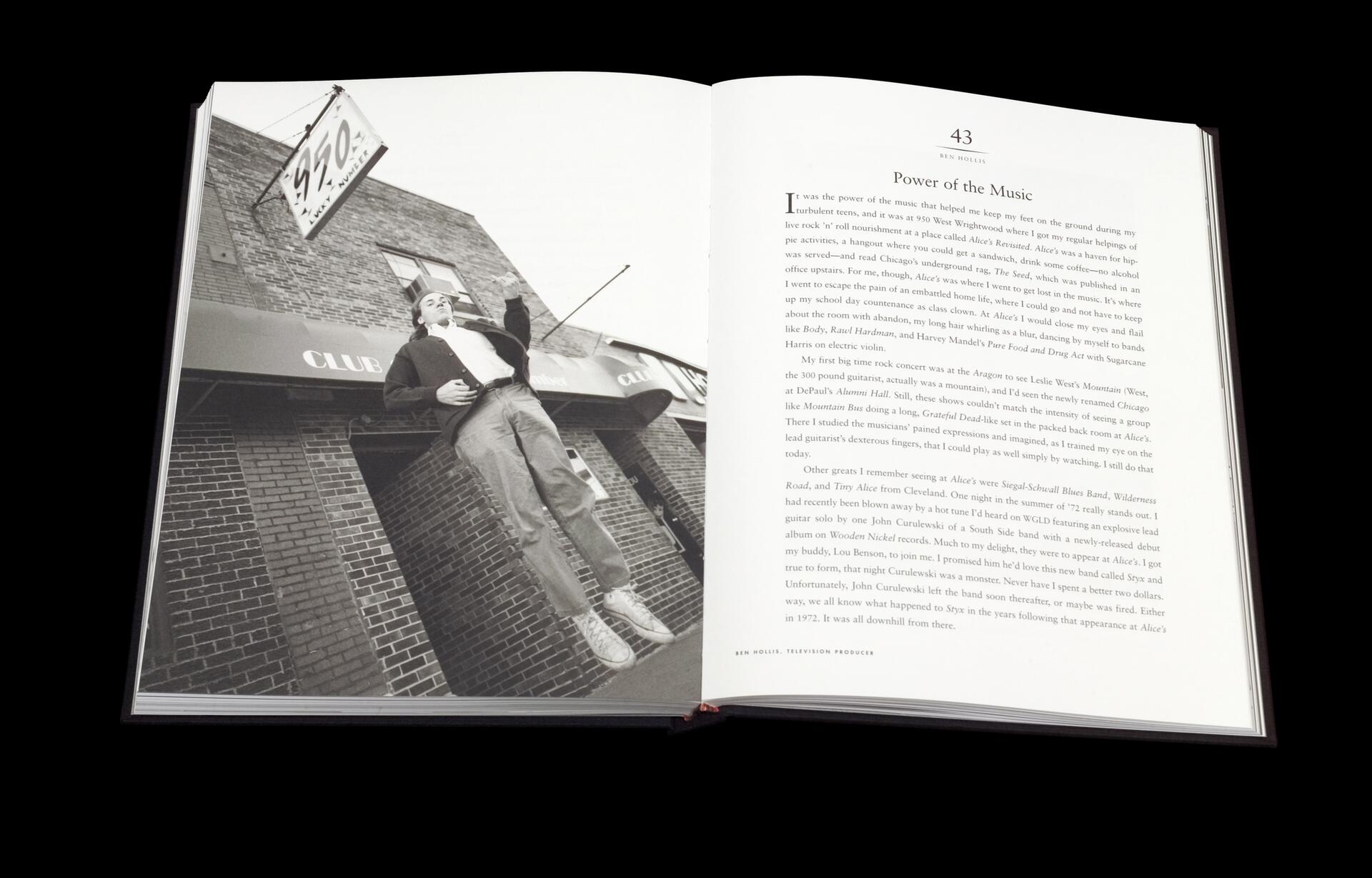 Open book with a black-and-white photograph on the left page showing a person standing casually outside a brick building with a sign above. The right page has an essay titled "Power of the Music" by Ben Hollis.